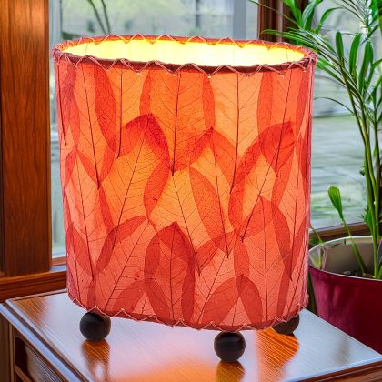 Crafted by the artisans of Eangee Home Design, the Mini Guyabano Table Lamp in red against a clean backdrop, featuring fossilized cocoa leaf shade, guyabano leaf shade, wrought iron frame.