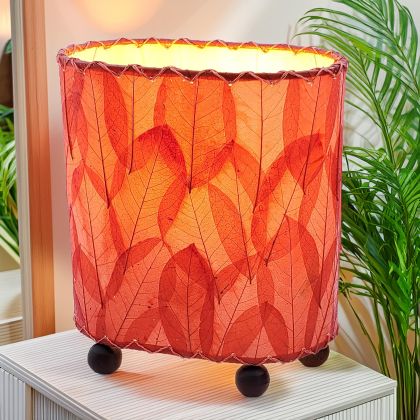 In a sun drenched entryway, crafted by the artisans of Eangee Home Design, the Mini Guyabano Table Lamp in red stands gracefully, featuring fossilized cocoa leaf shade, guyabano leaf shade, wrought iron frame, adding warmth and character to the space.