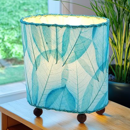 Crafted by the artisans of Eangee Home Design, the Mini Guyabano Table Lamp in sea blue against a clean backdrop, featuring fossilized cocoa leaf shade, guyabano leaf shade, wrought iron frame.