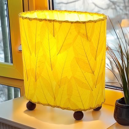 Crafted by the artisans of Eangee Home Design, the Mini Guyabano Table Lamp in yellow against a clean backdrop, featuring fossilized cocoa leaf shade, guyabano leaf shade, wrought iron frame.