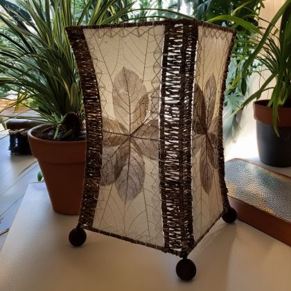 Crafted by the artisans of Eangee Home Design, the Hourglass Table Lamp in natural against a clean backdrop, featuring jackfruit leaf panels, abaca rope accents, wrought iron frame, eco friendly.