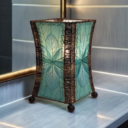 In a coastal inspired living room, crafted by the artisans of Eangee Home Design, the Hourglass Table Lamp in sea blue stands gracefully, featuring jackfruit leaf panels, abaca rope accents, wrought iron frame, eco friendly, adding warmth and character to the space.