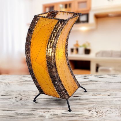 In a modern interior with earth tones, crafted by the artisans of Eangee Home Design, the C Shape Table Lamp in orange stands gracefully, featuring fossilized cocoa leaf shade, abaca rope accents, fair trade, handcrafted, adding warmth and character to the space.