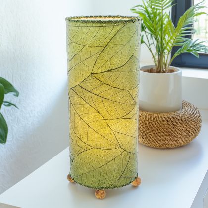 In a coastal inspired living room, crafted by the artisans of Eangee Home Design, the Cocoa Leaf Cylinder Table Lamp in green stands gracefully, featuring fossilized cocoa leaf shade, wrought iron frame, handcrafted, adding warmth and character to the space.