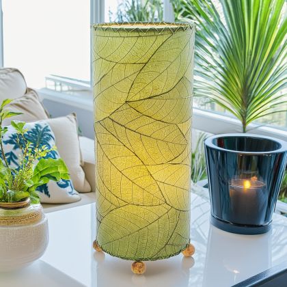 Slim cylinder table lamp crafted by Eangee Home Design in green fossilized cocoa leaves, each panel hand?laminated and stitched; minimalist form offers textural leaf detail while soft light pours through organic leaf texture; artisan?made from sustainable materials
