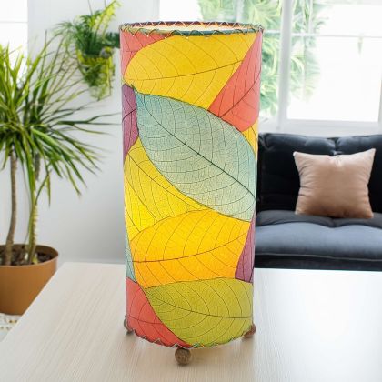 Slim cylinder table lamp crafted by Eangee Home Design in multi color fossilized cocoa leaves, each panel hand?laminated and stitched; minimalist form offers textural leaf detail while radiant light glows through organic leaf texture; artisan?made from sustainable materials