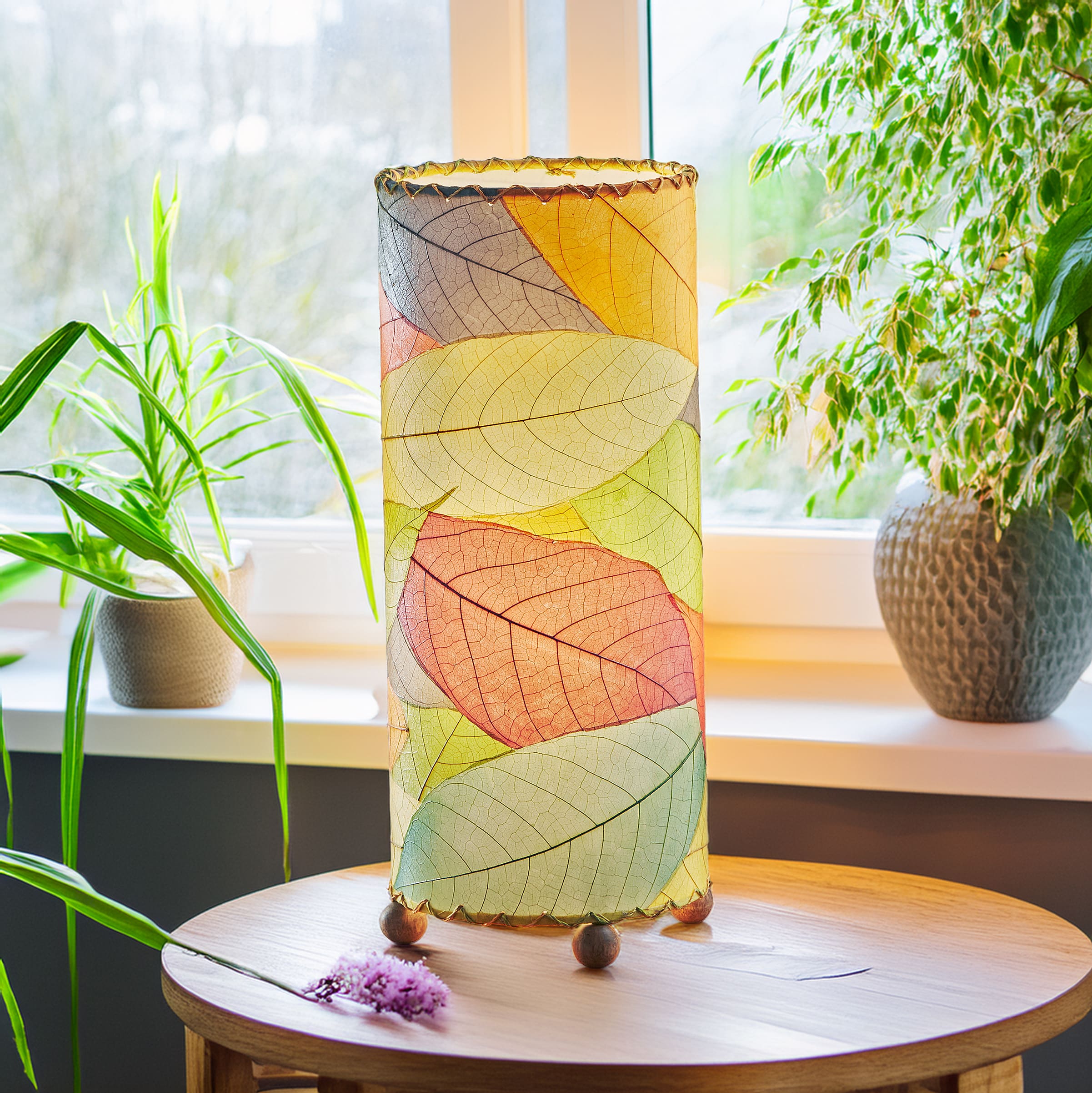 Eangee Home Design Cocoa Leaf Cylinder Table Lamp in Multi – Handcrafted from real fossilized cocoa leaves on a cylindrical UL-backed frame with natural wood feet. Fair-trade, eco-friendly lighting that adds colorful organic texture to modern and sustainable home décor.