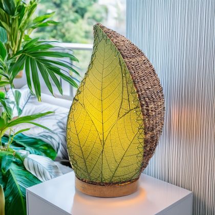 Leaf-shaped Leaflet Table Lamp crafted by Eangee Home Design, featuring green fossilized cocoa leaves stitched by hand onto wrought iron. The budding-leaf form breathes life as cozy light radiates through every vein, sustainably handcrafted by skilled artisans.