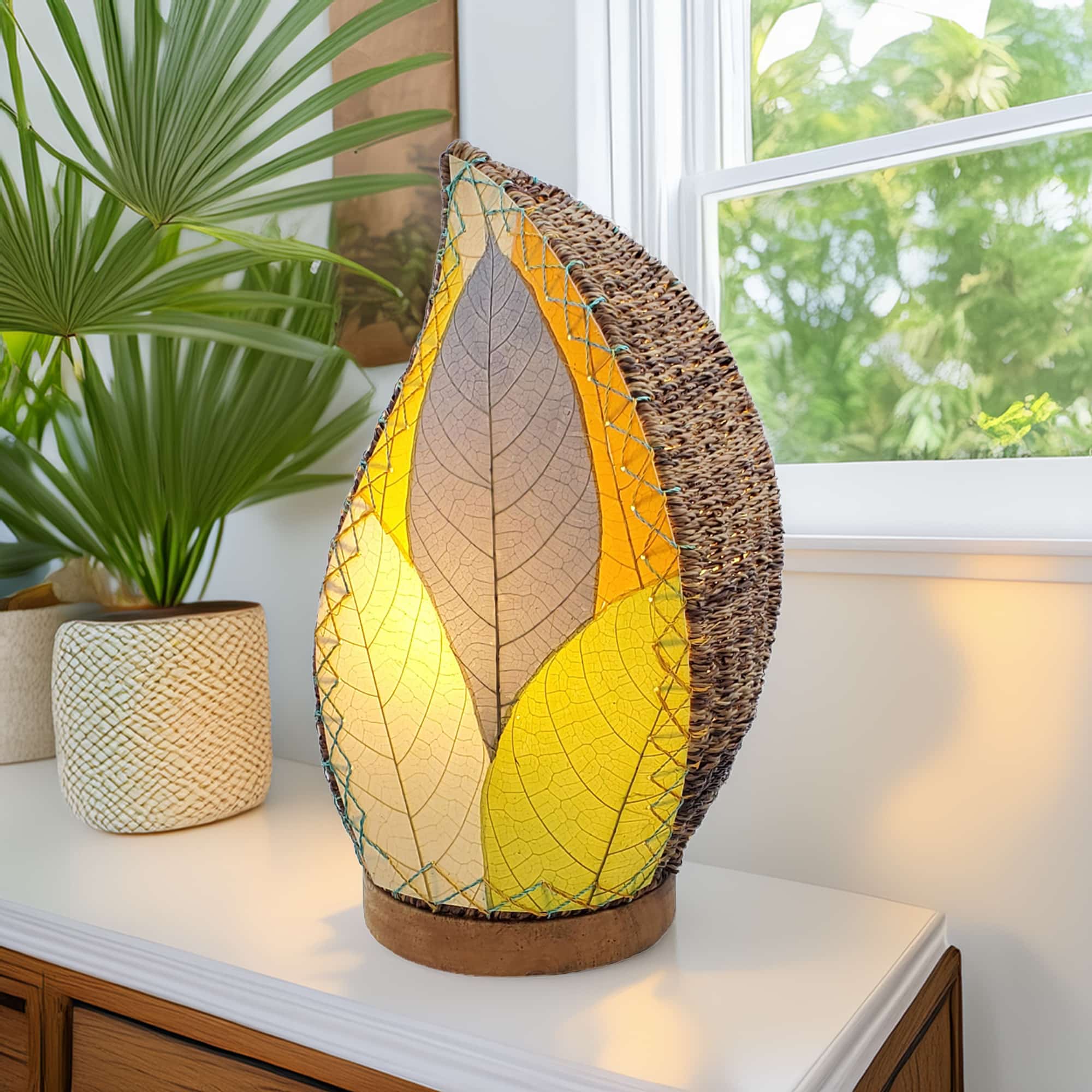 In a minimalist loft with natural textures, crafted by the artisans of Eangee Home Design, the Leaflet Table Lamp in multi color stands gracefully, featuring fossilized cocoa leaf shade, abaca rope accents, reclaimed mango wood base, wrought iron frame, sustainably sourced, adding warmth and character to the space.