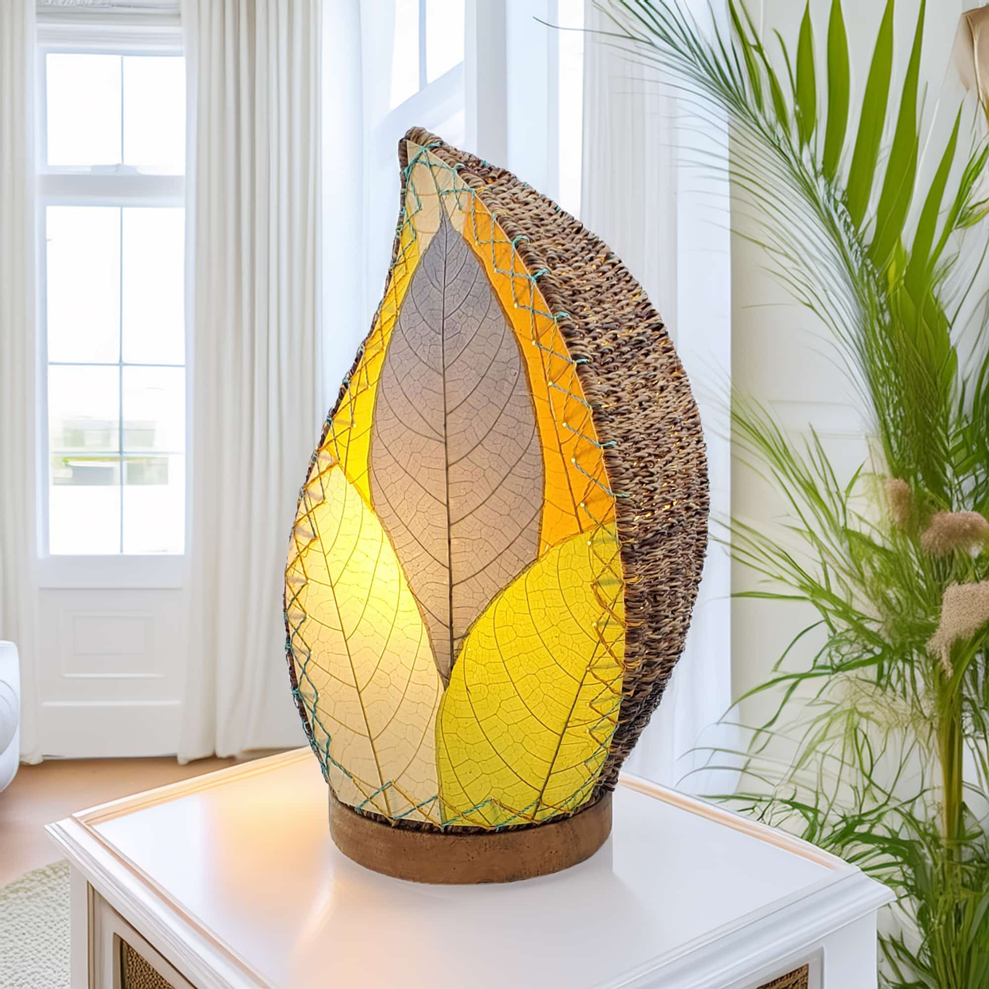 In a quiet bedside corner, crafted by the artisans of Eangee Home Design, the Leaflet Table Lamp in multi color stands gracefully, featuring fossilized cocoa leaf shade, abaca rope accents, reclaimed mango wood base, wrought iron frame, sustainably sourced, adding warmth and character to the space.