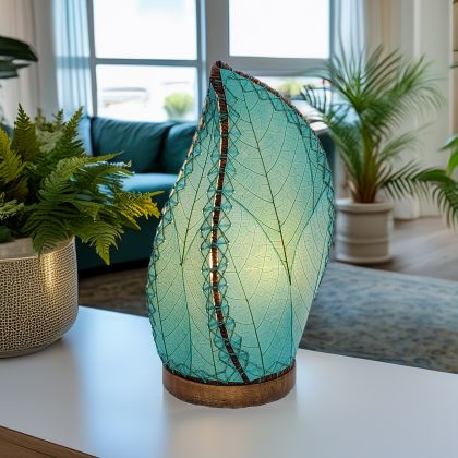 In a coastal inspired living room, crafted by the artisans of Eangee Home Design, the Leaflet Table Lamp in sea blue stands gracefully, featuring fossilized cocoa leaf shade, abaca rope accents, reclaimed mango wood base, wrought iron frame, sustainably sourced, adding warmth and character to the space.