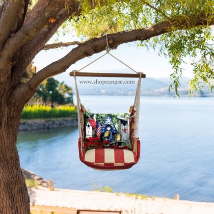 In a shaded porch swing a multi colored outdoor swing crafted by the artisans of Magnolia Casual called the Swing Set 4 piece Americana Stripe w/ Americana Birdhouses is displayed featuring 100 percent weather resistant fabric, weather resistant polyester fabric, handcrafted adding comfort and style to the space featuring with a stripe motif.