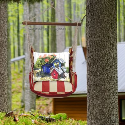 In a shaded porch swing a multi colored outdoor swing crafted by the artisans of Magnolia Casual called the Swing Set 4 piece Americana Stripe w/ Birdhouses & Flowers is displayed featuring 100 percent weather resistant fabric, weather resistant polyester fabric, handcrafted adding comfort and style to the space featuring with a stripe motif.