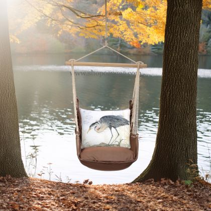 In an outdoor reading nook a multi colored outdoor swing crafted by the artisans of Magnolia Casual called the Swing Set 4 piece Chocolate Solid w/ Heron on Limb is displayed featuring 100 percent weather resistant fabric, weather resistant polyester fabric, artisan, natural materials adding comfort and style to the space.