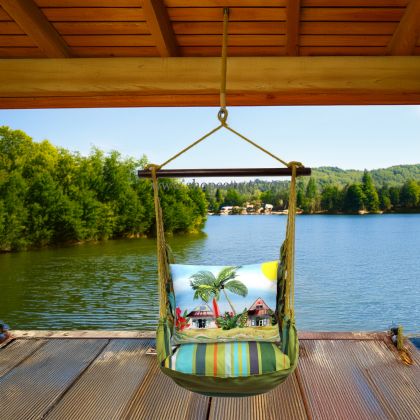 In a sunlit patio lounge a multi colored outdoor swing crafted by the artisans of Magnolia Casual called the Swing Set 4 piece Citrus Stripe w/ Surf Shack is displayed featuring 100 percent weather resistant fabric, weather resistant polyester fabric, handcrafted adding comfort and style to the space featuring with a stripe motif.