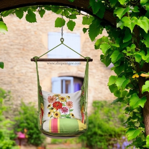 In an outdoor reading nook a multi colored outdoor swing crafted by the artisans of Magnolia Casual called the Swing Set 4 piece Fresh Lime Stripe w/ Zinnias is displayed featuring 100 percent weather resistant fabric, weather resistant polyester fabric, handcrafted adding comfort and style to the space featuring with a stripe motif and shades of lime.