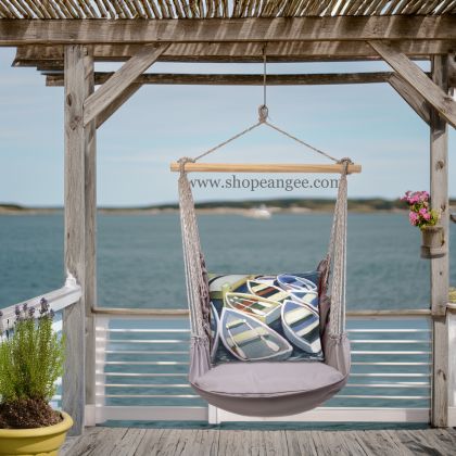 In an outdoor reading nook a gray outdoor swing crafted by the artisans of Magnolia Casual called the Swing Set 4 piece Gray Solid w/ Boats is displayed featuring 100 percent weather resistant fabric, weather resistant polyester fabric, handcrafted adding comfort and style to the space featuring shades of gray.