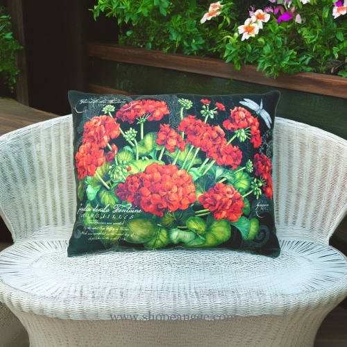 In an outdoor reading nook a red outdoor pillow crafted by the artisans of Magnolia Casual called the Outdoor Pillow Red Geranium is displayed featuring handwoven textile adding comfort and style to the space featuring shades of red.