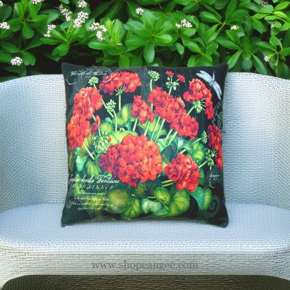 In an outdoor reading nook a red outdoor pillow crafted by the artisans of Magnolia Casual called the Outdoor Pillow Red Geranium is displayed featuring handwoven textile adding comfort and style to the space featuring shades of red.