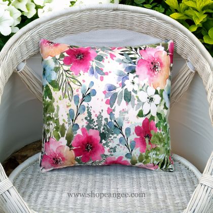 In a shaded porch swing a multi colored outdoor pillow crafted by the artisans of Magnolia Casual called the Outdoor Pillow Meadow Dance 1 18x18 is displayed featuring 100 percent weather resistant fabric adding comfort and style to the space.