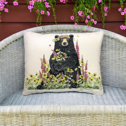 In a shaded porch swing a multi colored outdoor pillow crafted by the artisans of Magnolia Casual called the Outdoor Pillow Wildflower & Bear 19x24 is displayed featuring handwoven textile adding comfort and style to the space.