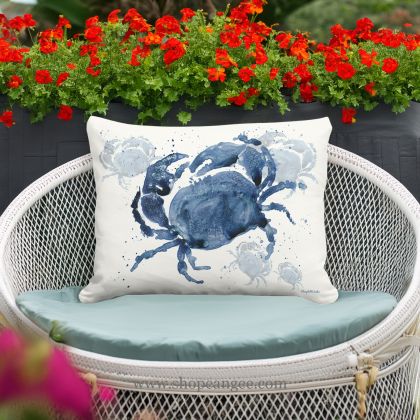 In a coastal inspired deck chair a multi colored outdoor pillow crafted by the artisans of Magnolia Casual called the Outdoor Pillow Indigo Crab 19x24 is displayed featuring quality outdoor fabric adding comfort and style to the space featuring with a crab motif.