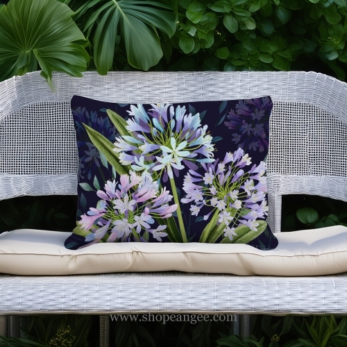 In a cozy garden seating area a multi colored outdoor pillow crafted by the artisans of Magnolia Casual called the Outdoor Pillow Midnight Garden Lilies 19x24 is displayed featuring handwoven textile adding comfort and style to the space.