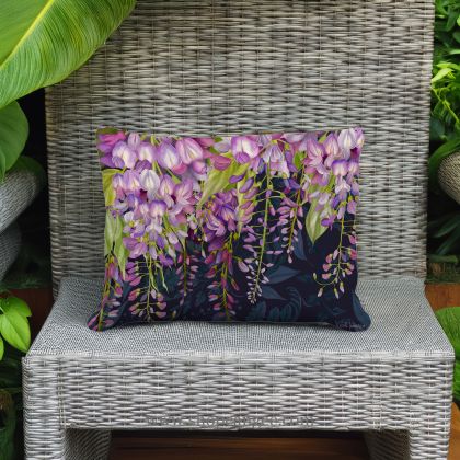 In a cozy garden seating area a multi colored outdoor pillow crafted by the artisans of Magnolia Casual called the Outdoor Pillow Midnight Garden Wisteria 19x24 is displayed featuring handwoven textile adding comfort and style to the space.
