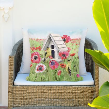 In a sunlit patio lounge a yellow outdoor pillow crafted by the artisans of Magnolia Casual called the Outdoor Pillow Yellow Birds and Poppy Field 18x18 is displayed featuring handwoven textile adding comfort and style to the space featuring shades of yellow.
