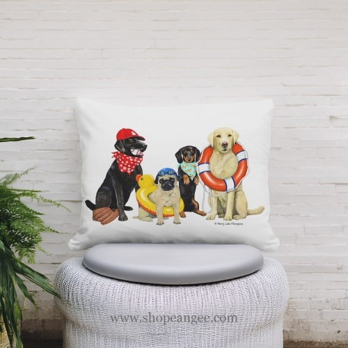 In a sunlit patio lounge a multi colored outdoor pillow crafted by the artisans of Magnolia Casual called the Outdoor Pillow Dogs of Summer 13x18 is displayed featuring quality outdoor fabric adding comfort and style to the space.