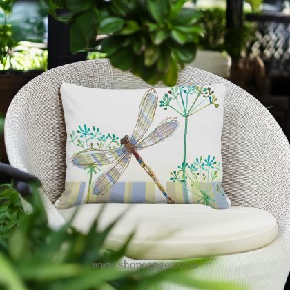 In a shaded porch swing a multi colored outdoor pillow crafted by the artisans of Magnolia Casual called the Outdoor Pillow Dragonfly Wisp 19x24 is displayed featuring quality outdoor fabric adding comfort and style to the space featuring with a dragonfly motif.
