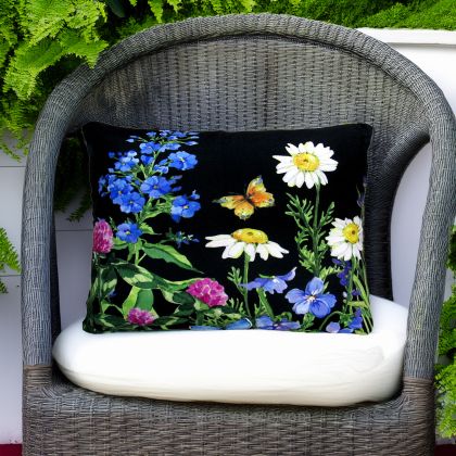 In a cozy garden seating area a multi colored outdoor pillow crafted by the artisans of Magnolia Casual called the Outdoor Pillow Garden Meadow 2 is displayed featuring handwoven textile adding comfort and style to the space.