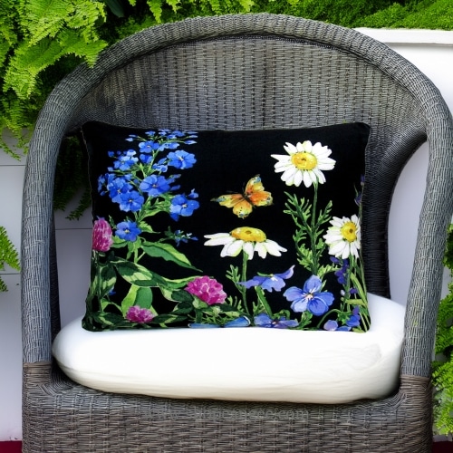 In a cozy garden seating area a multi colored outdoor pillow crafted by the artisans of Magnolia Casual called the Outdoor Pillow Garden Meadow 2 is displayed featuring handwoven textile adding comfort and style to the space.