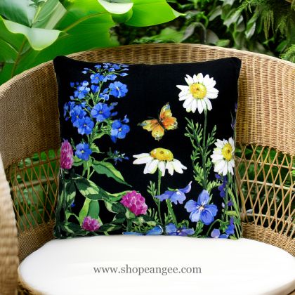 In a cozy garden seating area a multi colored outdoor pillow crafted by the artisans of Magnolia Casual called the Outdoor Pillow Garden Meadow 2 is displayed featuring handwoven textile adding comfort and style to the space.