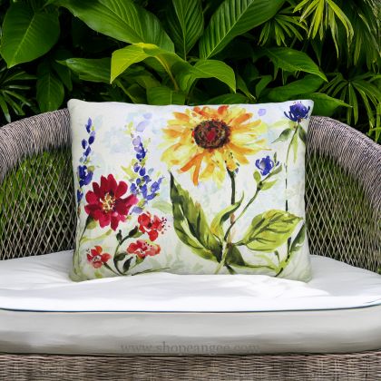 In an outdoor reading nook a multi colored outdoor pillow crafted by the artisans of Magnolia Casual called the Outdoor Pillow Sunflower Field 19x24 is displayed featuring handwoven textile adding comfort and style to the space featuring with a sunflower motif.