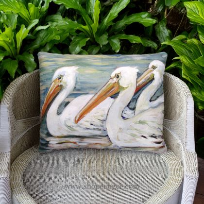 In a shaded porch swing a multi colored outdoor pillow crafted by the artisans of Magnolia Casual called the Outdoor Pillow 3 Pelicans Swimming 19x24 is displayed featuring quality outdoor fabric adding comfort and style to the space.