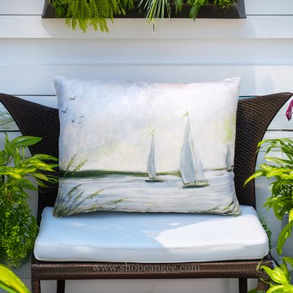 In a poolside chaise a multi colored outdoor pillow crafted by the artisans of Magnolia Casual called the Outdoor Pillow Sailboats 19x24 is displayed featuring quality outdoor fabric adding comfort and style to the space.