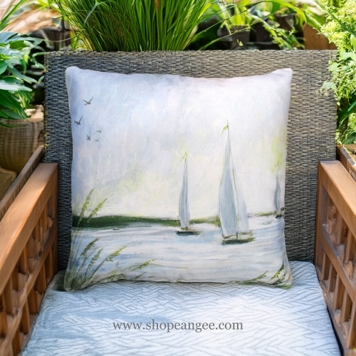 In a cozy garden seating area a multi colored outdoor pillow crafted by the artisans of Magnolia Casual called the Outdoor Pillow Sailboats 18x18 is displayed featuring quality outdoor fabric adding comfort and style to the space.