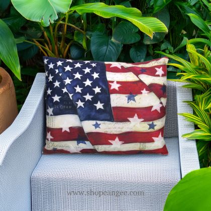 In a cozy garden seating area a multi colored outdoor pillow crafted by the artisans of Magnolia Casual called the Outdoor Pillow American Flag with Stars 19x24 is displayed featuring quality outdoor fabric adding comfort and style to the space.
