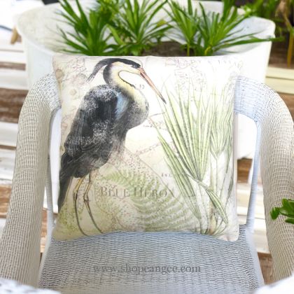 In a cozy garden seating area a multi colored outdoor pillow crafted by the artisans of Magnolia Casual called the Outdoor Pillow Great Heron 1 18x18 is displayed featuring quality outdoor fabric, natural materials adding comfort and style to the space.