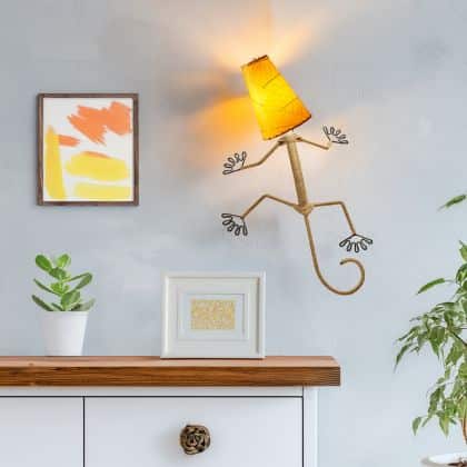 Eangee Home Design Gecko Wall Sconce in orange with a shade made of real cocoa leaves, playful lizard lamp adding warm glow to a contemporary hallway