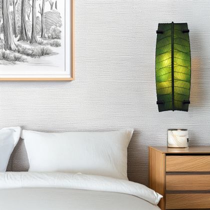 Eangee Home Design Banana Wall Sconce in green with a shade made of real cocoa leaves, softly illuminating a contemporary bedroom beside a framed forest sketch